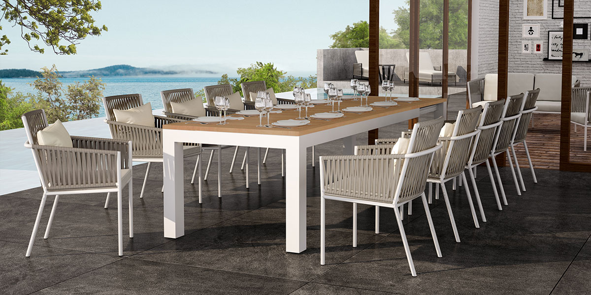 Loom Crafts Outdoor Garden Furniture An outdoor dining table with chairs and a view of the ocean.