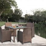 Loom Crafts Outdoor Garden Furniture A wicker dining set on a dock near a lake.