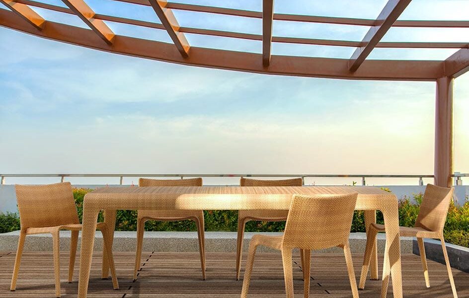 Loom Crafts Outdoor Garden Furniture A wooden table and chairs on a deck overlooking the ocean.