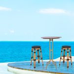Loom Crafts Outdoor Garden Furniture A table with two BAR STOOL LCBS.001.003 and a view of the ocean.