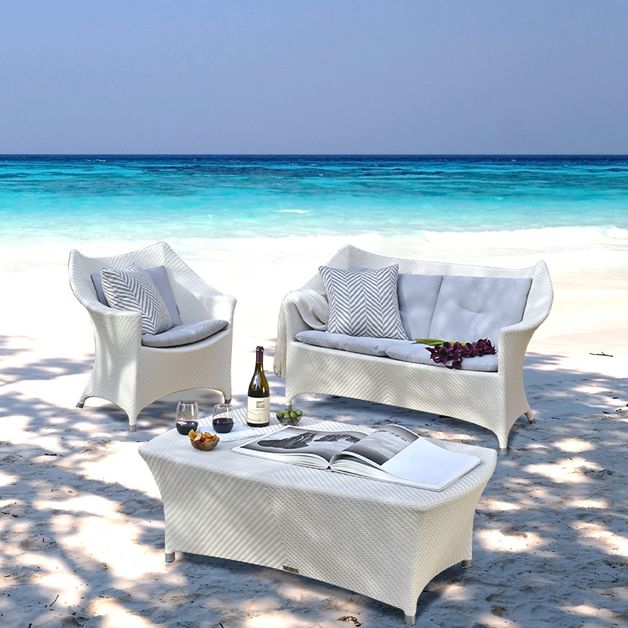 Loom Crafts Outdoor Garden Furniture A white wicker furniture set on the beach.